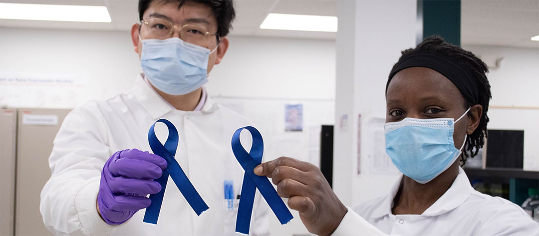 Two Norgen scientists holding up blue colorectal cancer awareness ribbons